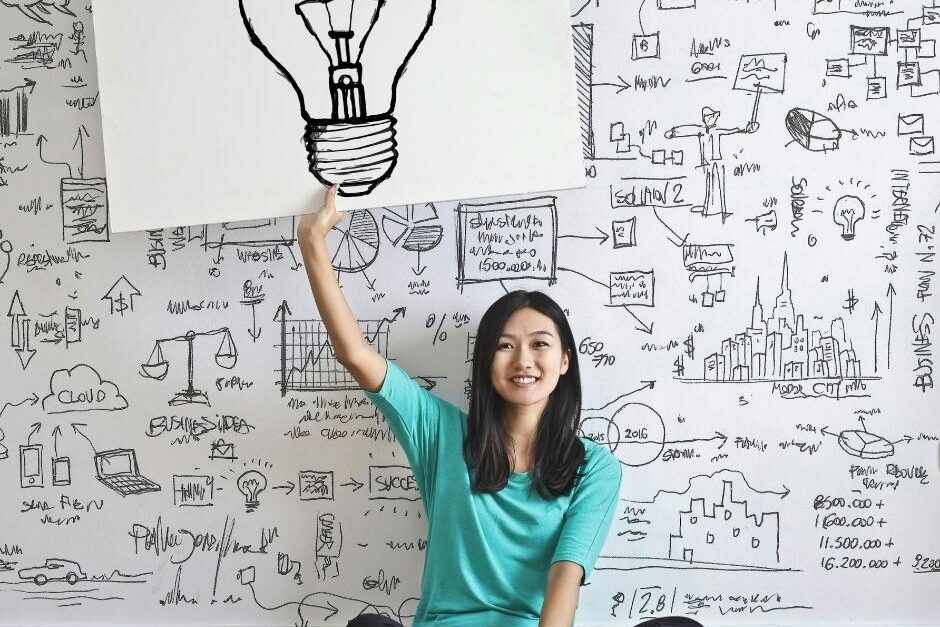 A girl holding a board up that has a bulb drawn